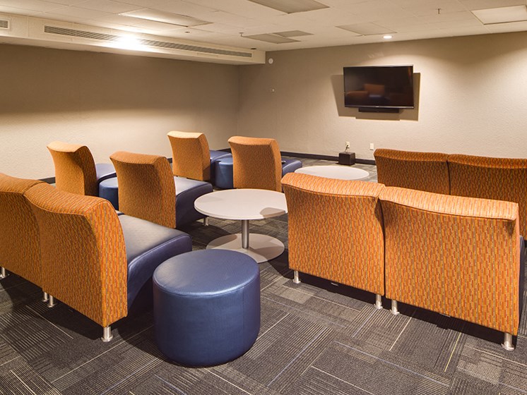 media room with three rows of orange chairs looking towards TV mounted on the wall